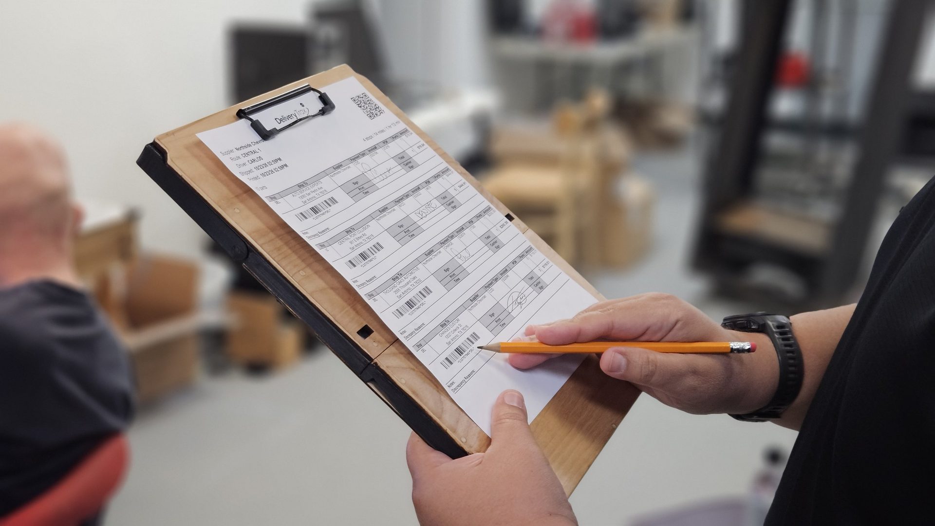 Driver signing a route sheet clipped to the DeskDrive Pro clipboard