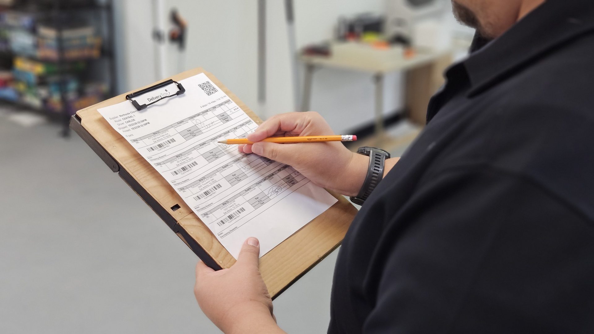 Side view of a driver writing on a route sheet on the DeskDrive Pro clipboard