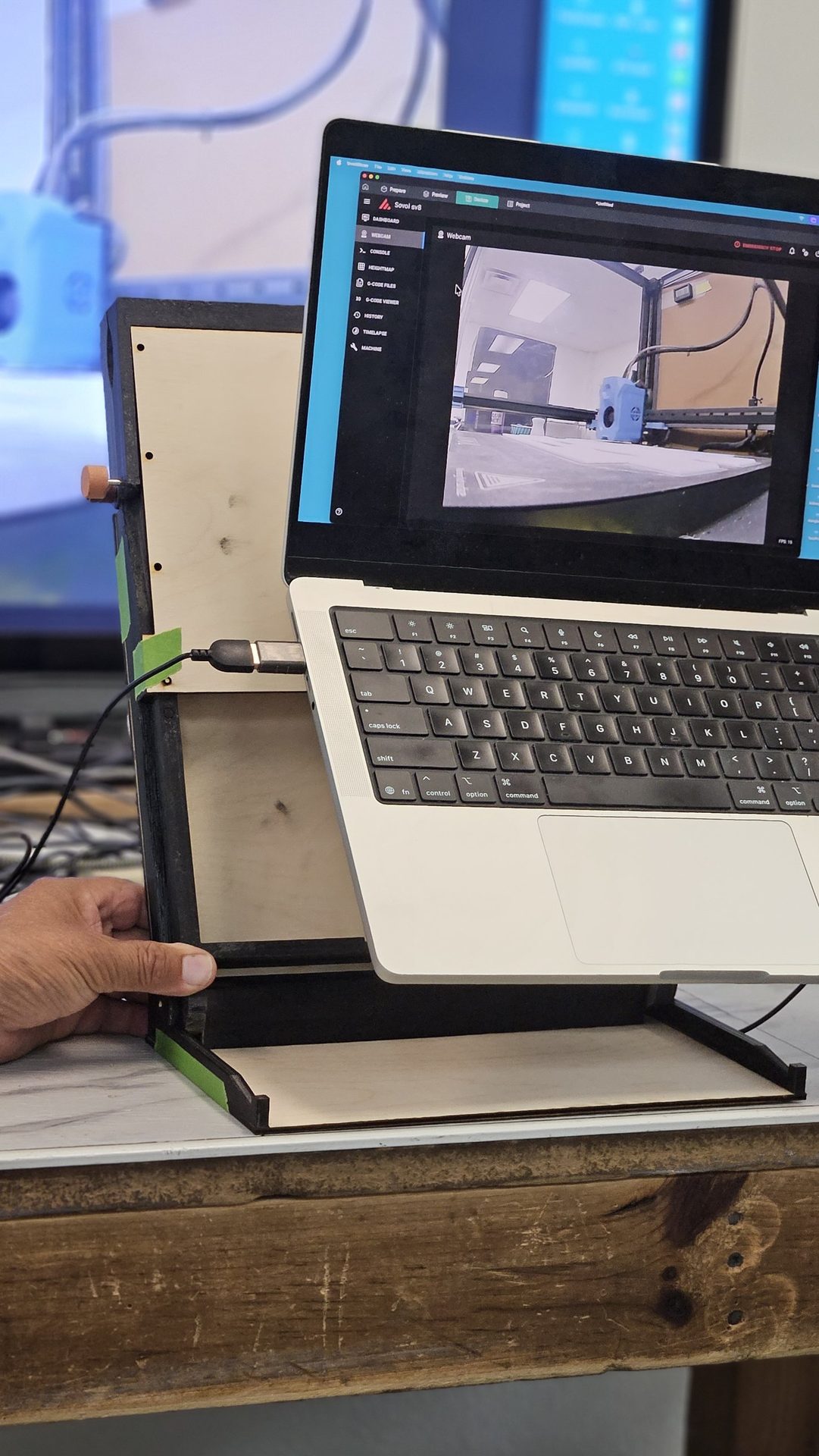 Side view of DeskDrive Pro unfolded as a laptop stand, with the fold-out base on the bench